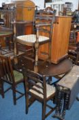 AN OAK CIRCULAR EXTENDING DINING TABLE, and four chairs including one carver (5)