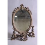 A 19TH CENTURY STYLE BRONZED OVAL TOILET MIRROR, surmounted by a cartouche and flowers, cast foliate