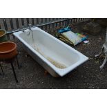 A CAST IRON BATH, with stands and taps, approximate length 156cm x width 64cm