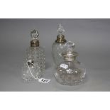 THREE EARLY 20TH CENTURY CLEAR GLASS SCENT/TOILET BOTTLES WITH SILVER COLLARS, together with a