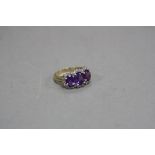 A MODERN AMETHYST AND DIAMOND DRESS RING, three oval mixed cut amethyst stones enclosed within a