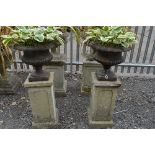 A PAIR OF CAST IRON CAMPANA STYLE URNS, on precast square columns, approximate total height 115cm