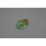 A JADEITE PENDANT, jadeite disk measuring approximately 20mm in width, Oriental design, foliate cap,