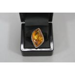 A LARGE SILVER RING, set with amber, ring size R