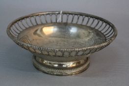 A GEORGE V CIRCULAR SILVER FRUIT BOWL, gadrooned rim, arched design open wire border, the centre