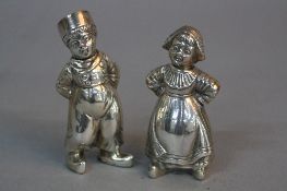 A NEAR PAIR OF 20TH CENTURY CONTINENTAL SILVER PEPPERETTES, in the form of a Dutch Boy and Girl,
