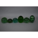 A VICTORIAN GREEN GLASS DUMP PAPERWEIGHT, seven flower inclusions over three tiers, height