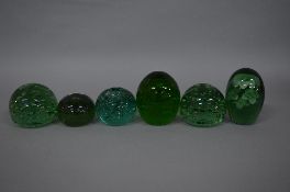 A VICTORIAN GREEN GLASS DUMP PAPERWEIGHT, seven flower inclusions over three tiers, height
