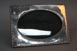 A GEORGE V RECTANGULAR SILVER PHOTOGRAPH FRAME, with oval glazed opening, bobbin moulded borders,
