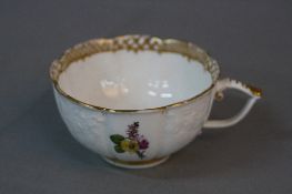A 19TH CENTURY MEISSEN TEA CUP, of wavy outline, gilt border to the interior with flower spray,