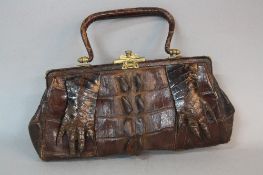 A VINTAGE CROCODILE SKIN HANDBAG, dark brown, with two feet on front, repairs to handle fastening,