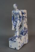 A MODERN CERAMIC BOOKEND MODELLED AS A MALE NUDE LEANING BACK AGAINST THE UPRIGHT, transfer