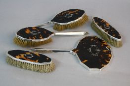 A GEORGE V FIVE PIECE SILVER AND TORTOISESHELL DRESSING TABLE SET, pique work swagged oval design,
