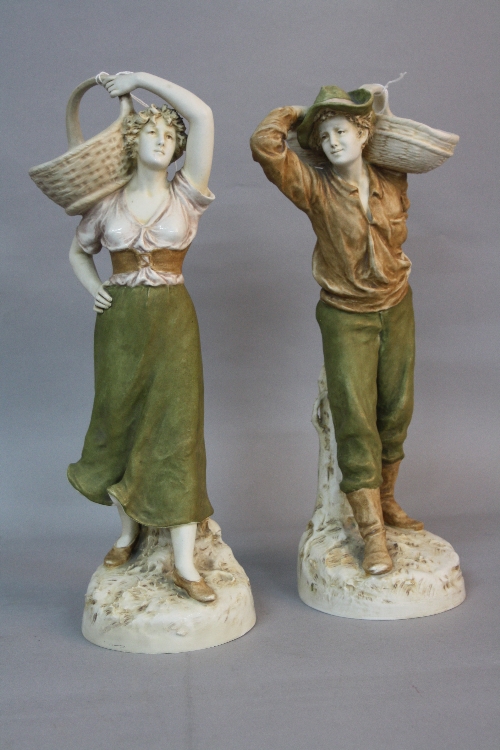 A PAIR OF EARLY 20TH CENTURY ROYAL DUX FIGURES OF A YOUNG MAN AND WOMAN, both with a basket on their