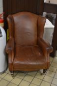 A TAN LEATHER LAURA ASHLEY WING BACK ARMCHAIR, on brass caps and casters