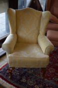 A GOLD UPHOLSTERED WING BACK ARMCHAIR