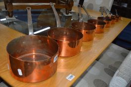 A SET OF EIGHT GRADUATING COPPER PANS, with hooped iron handles