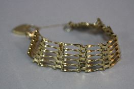 A LATE 20TH CENTURY 9CT GOLD SIX BAR STRAIGHT GATE BRACELET, fitted to a padlock and safety chain,