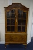 A WALNUT GLAZED TWO DOOR CABINET, above cupboard base, with arched top on cabriole feet