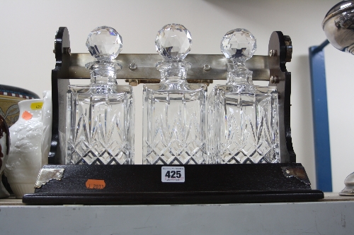 A MODERN TANTALUS, fitted with three square glass decanters in a wooden frame with plated mounts