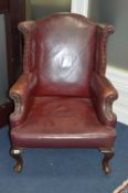 A VICTORIAN BURGUNDY LEATHER WING BACK ARMCHAIR, on front brass casters