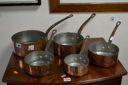 A SET OF FIVE GRADUATING COPPER PANS, with iron hooped handles
