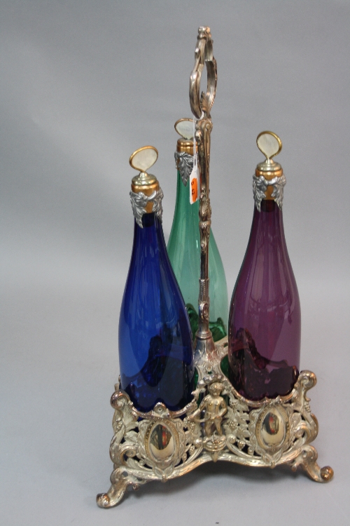 A SILVER PLATED VICTORIAN STYLE THREE BOTTLE DECANTER STAND, with three coloured glass bottles,