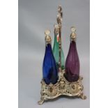 A SILVER PLATED VICTORIAN STYLE THREE BOTTLE DECANTER STAND, with three coloured glass bottles,