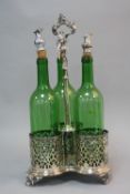 A LATE VICTORIAN THREE BOTTLE DECANTER STAND, foliate pierced design, with three green glass bottles