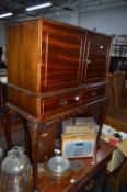 A MAHOGANY TWO DOOR DRINKS CABINET, on cabriole legs with a single drawer (key)