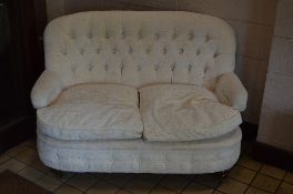 A MODERN UPHOLSTERED BUTTON BACK TWO SEATER SETTEE