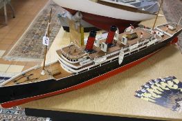A POWERED MODEL OF A TWO FUNNEL OCEAN LINER, red and black livery similar to Cunard, of wooden and