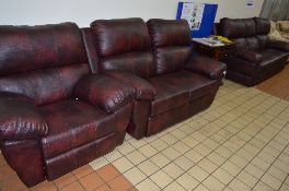 A BURGUNDY LEATHER STYLE THREE PIECE SUITE, comprising of three seater settee, two seater settee and