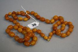 A DOUBLE STRING OF SIXTY SEVEN OLD AMBER BEADS, different shapes and sizes, approximate length 67cm,