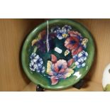 A MOORCROFT POTTERY PLATE, 'Orchid' pattern on a green ground, impressed marks and painted signature