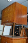 A TEAK RECORD CABINET WITH FALL FRONT ON RAOSED LEGS, a modern dining table and two chairs (4)