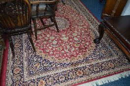 A LATE 20TH CENTURY MACHINE WOVEN SILK EFFECT CARPET SQUARE, claret and navy blue ground, foliate
