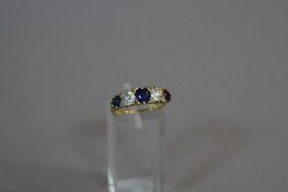 A SAPPHIRE AND DIAMOND RING, with three graduated round cut sapphires and two old round cut