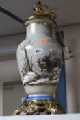 A TABLE LAMP, decorated with Stags in snowy landscape, with brass mounts and plinth, height