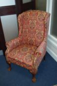 AN UPHOLSTERED WING BACK ARMCHAIR, on ball and claw feet