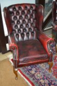 AN OX BLOOD BUTTONED WING BACK ARMCHAIR, approximate size height 97cm and inner arm width 43cm