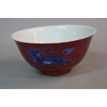 A CHINESE PORCELAIN BOWL, the iron red ground decorated with dragon dogs and flaming pearls, blue