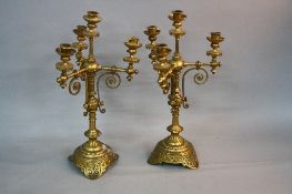 A PAIR OF VICTORIAN GOTHIC GILT METAL CANDELABRA, four branch with circular drip pans on turned arms