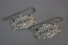 A PAIR OF SILVER WINE LABELS, on short chains with foliate and shell embossed decoration, pierced
