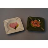 TWO MOORCROFT POTTERY ASH TRAYS, 'Magnolia' on cream ground and 'Hibiscus' on green ground, both