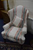 AN UPHOLSTERED WING BACK ARMCHAIR, on ball and claw feet, approximate size inner arm width 52cm x