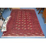 A 20TH CENTURY COUCASION WOOL RUG, red ground, multi strap border surrounding a geometric design,