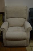 A BEIGE UPHOLSTERED RECLINING ARMCHAIR