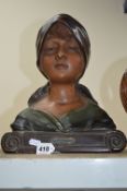 AN EARLY 20TH CENTURY PAINTED PLASTER BUST OF A GIRL WEARING A HEAD SCARF, titled ''Au Village''