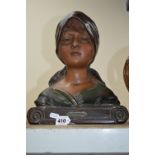 AN EARLY 20TH CENTURY PAINTED PLASTER BUST OF A GIRL WEARING A HEAD SCARF, titled ''Au Village''